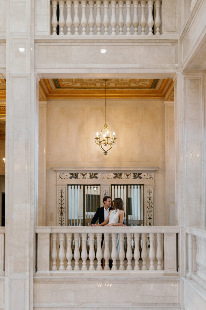 Engaged couple sharing a quiet moment in front of decorative elevator doors at Book Tower during their Detroit Book Tower engagement session