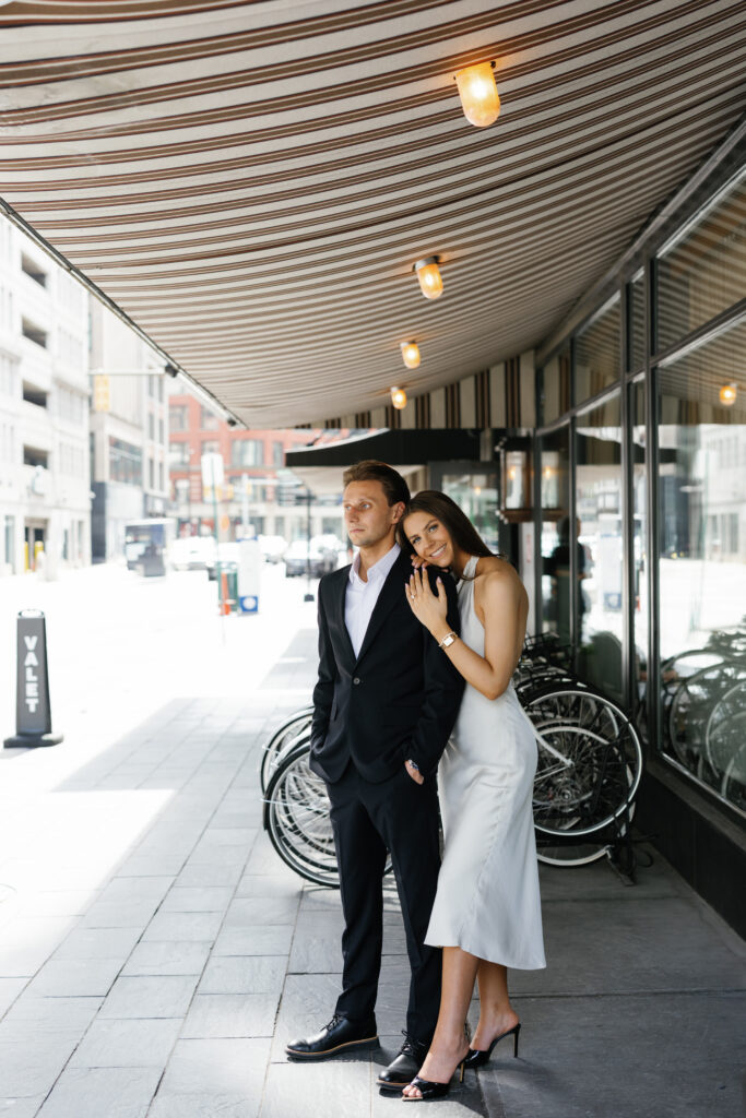 Engaged couple standing under the striped overhang at Shinola Hotel in downtown Detroit during their Detroit Book Tower engagement session