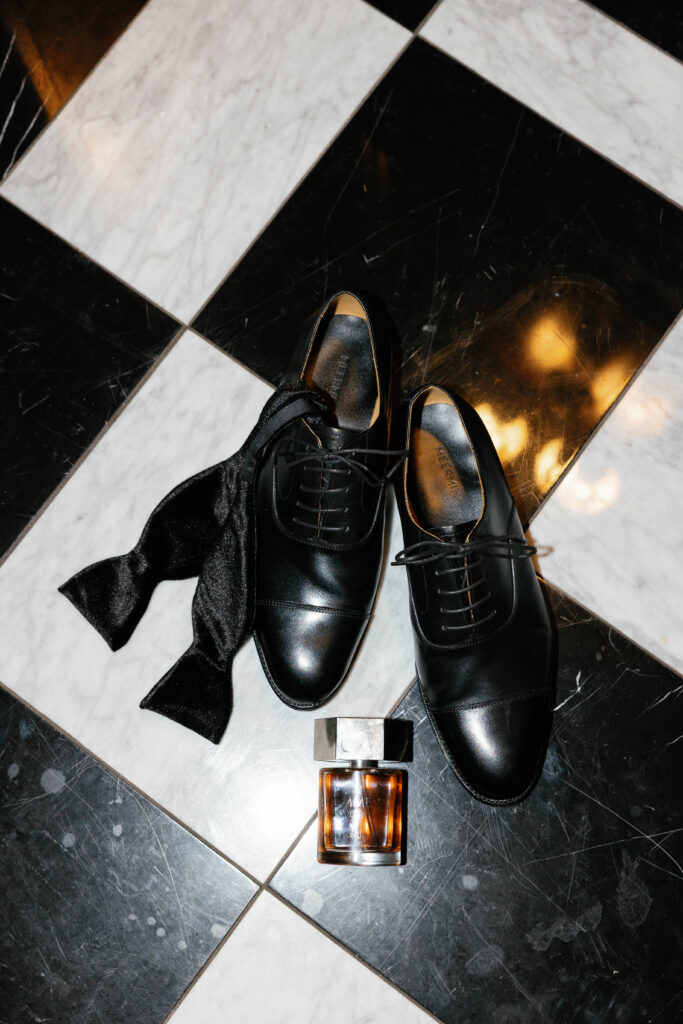 groom's shoes, bowtie, cologne on checkered floor in the graduate hotel in Ann Arbor Michigan