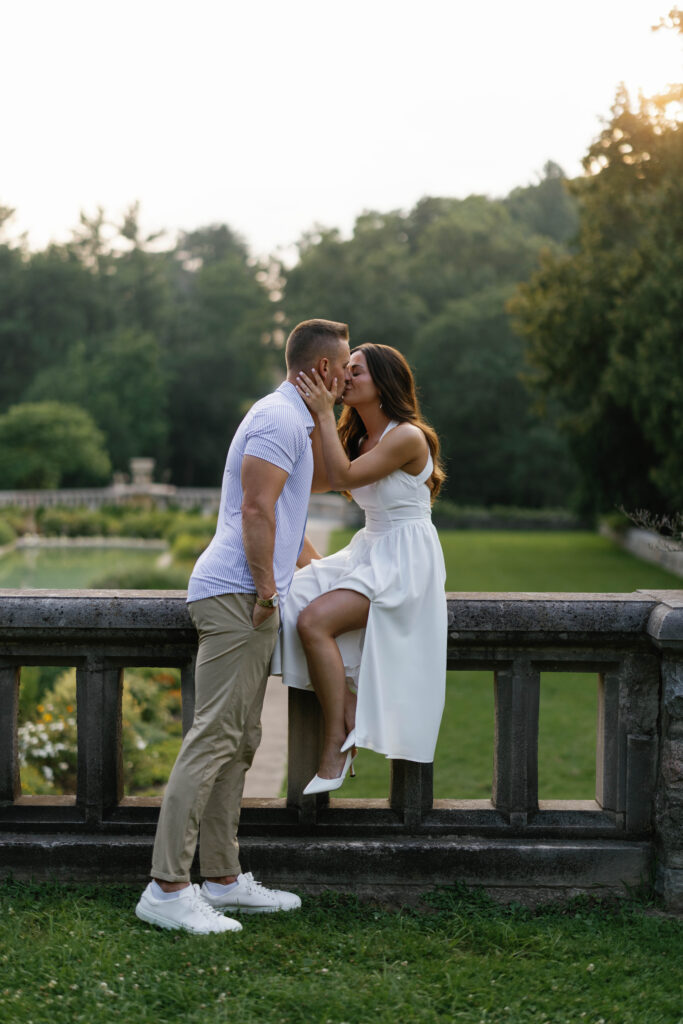 black and white bride to be sitting on stone railing couple holding each others faces close