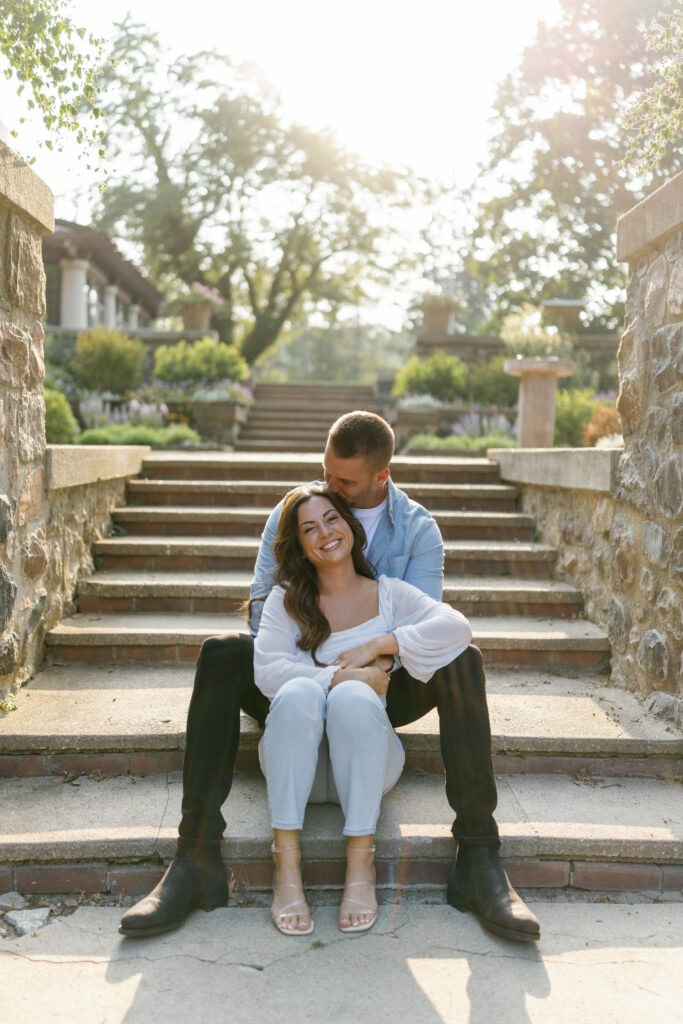 Couple sitting on stone steps at Cranbrook House & Gardens during Detroit engagement session.