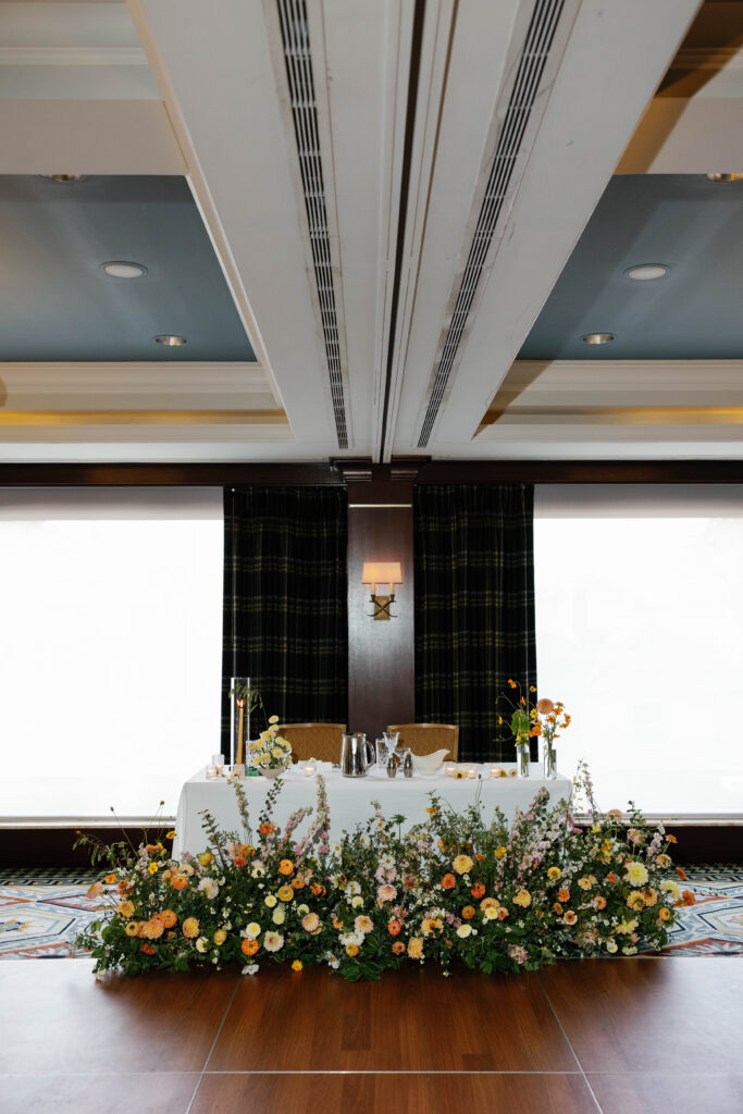 bride and groom sweetheart table decorated with florals at the bottom.