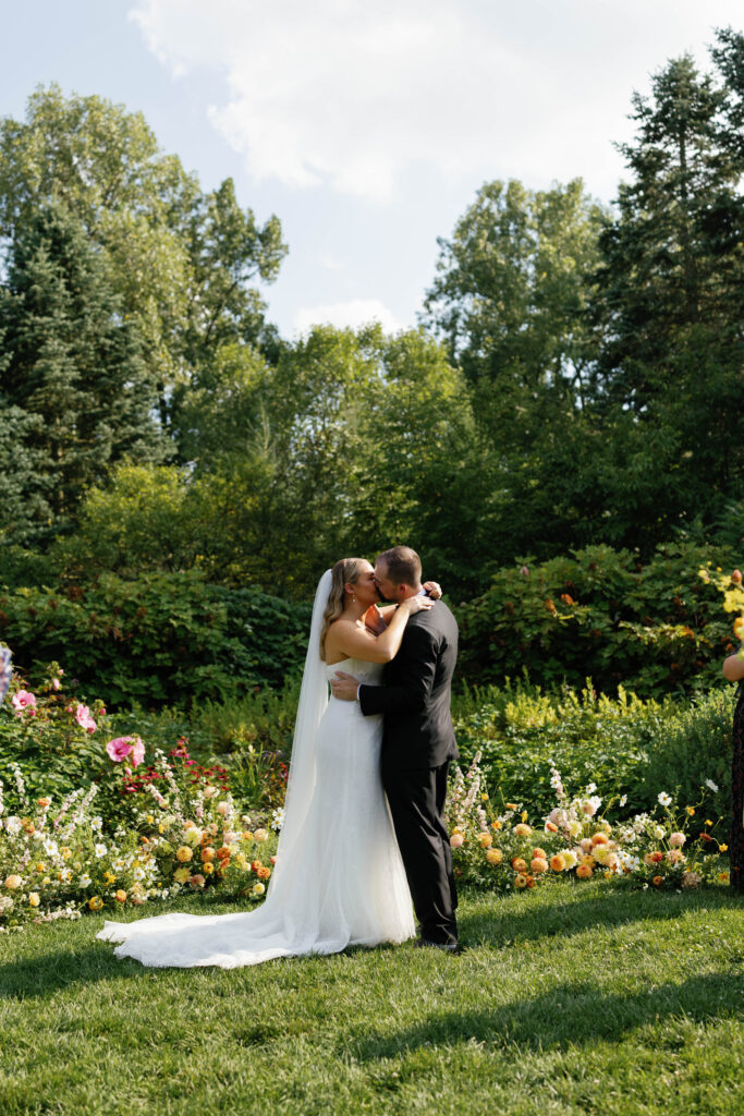 Bride and groom's first kiss during ceremony at Matthaei Botanical Garden