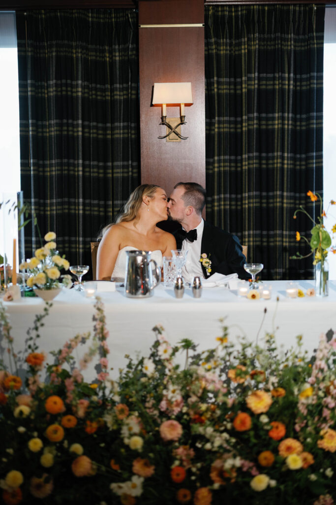 bride and groom kiss at head table