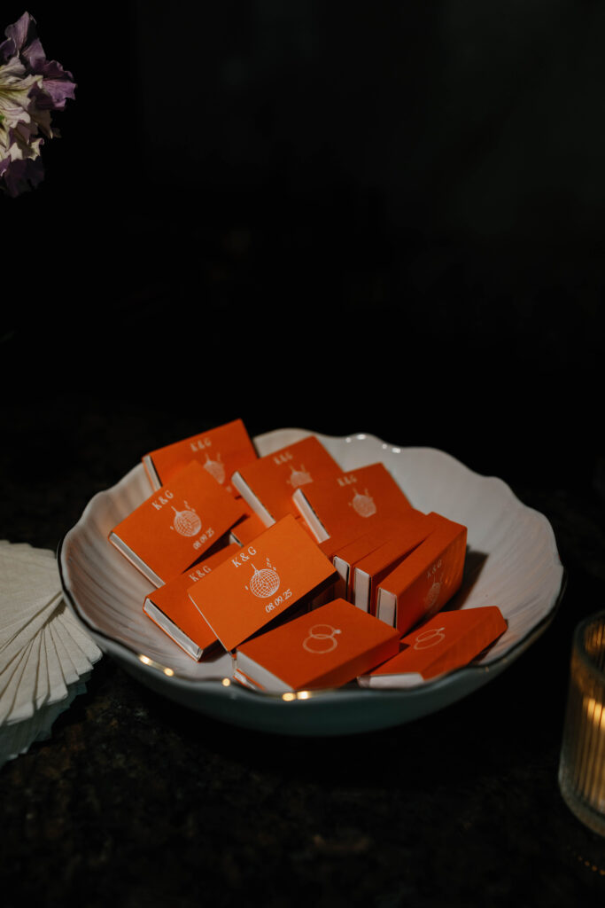 Custom orange matches with bride and groom's initials on top, disco ball in the middle and wedding date on bottom.