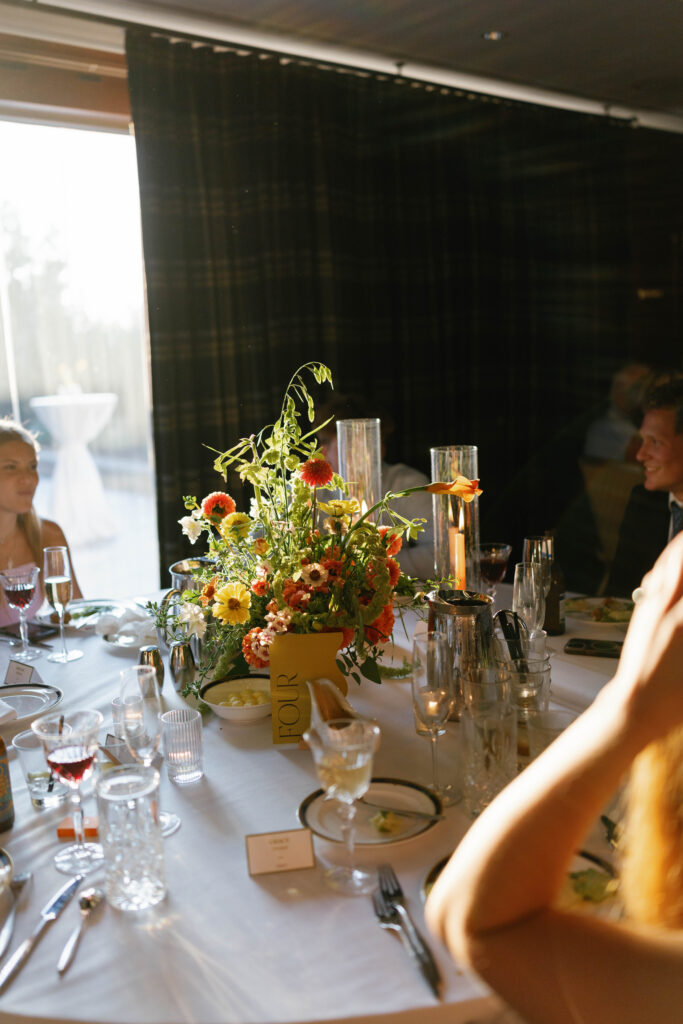 Golden light filtering behind a floral centerpiece on a reception table.