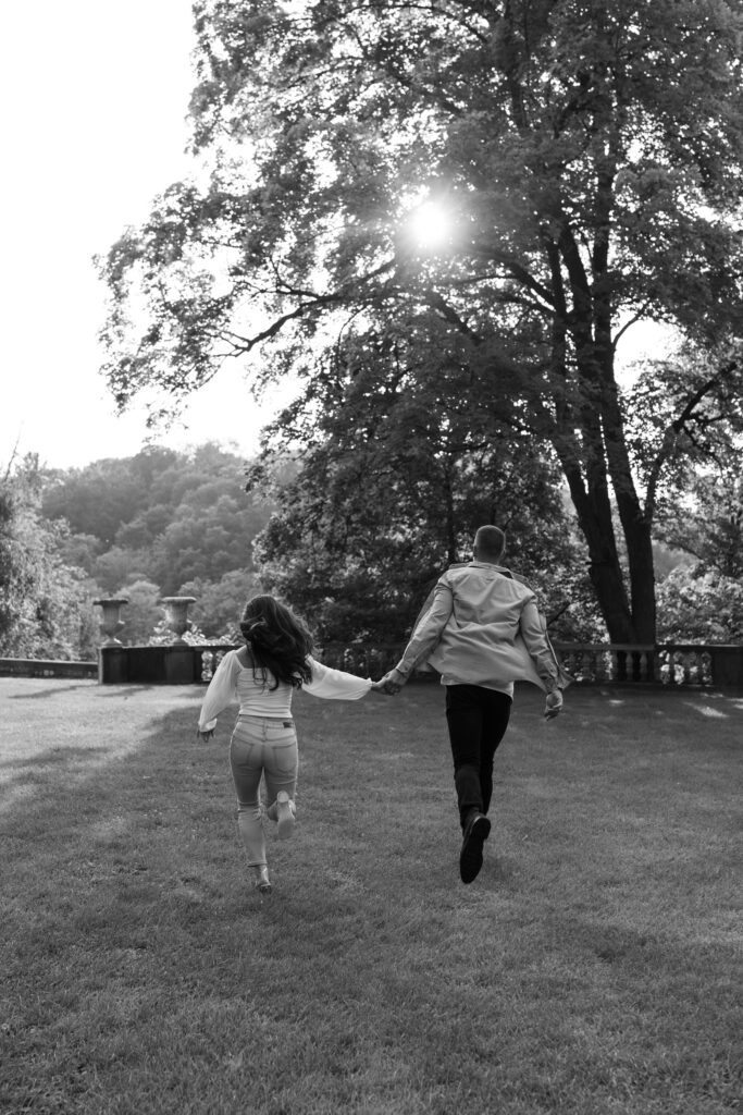 Black and white photo of couple running in open lawn at Cranbrook engagement session.