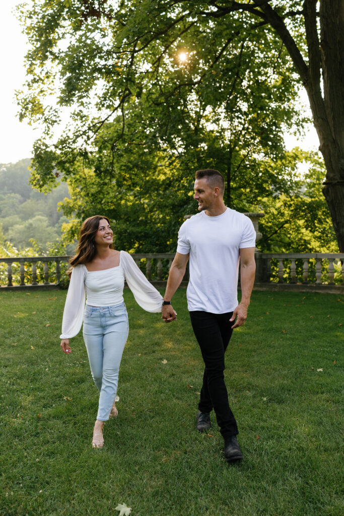 Playful engagement session moment walking hand in hand at Cranbrook House & Gardens