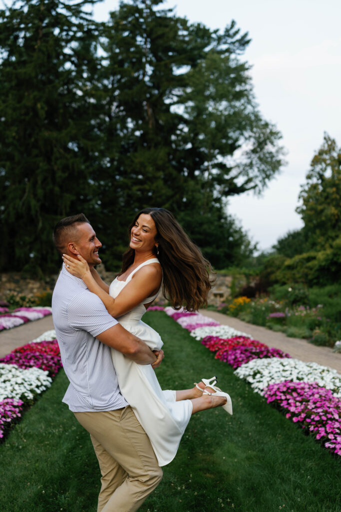 Romantic spin in colorful flower beds during Cranbrook engagement photos.