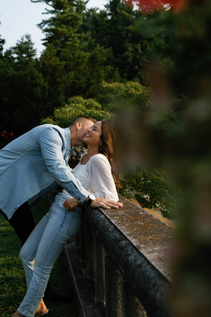 Intimate portrait groom leaning into bride on stone railing at Cranbrook House during Detroit engagement session.