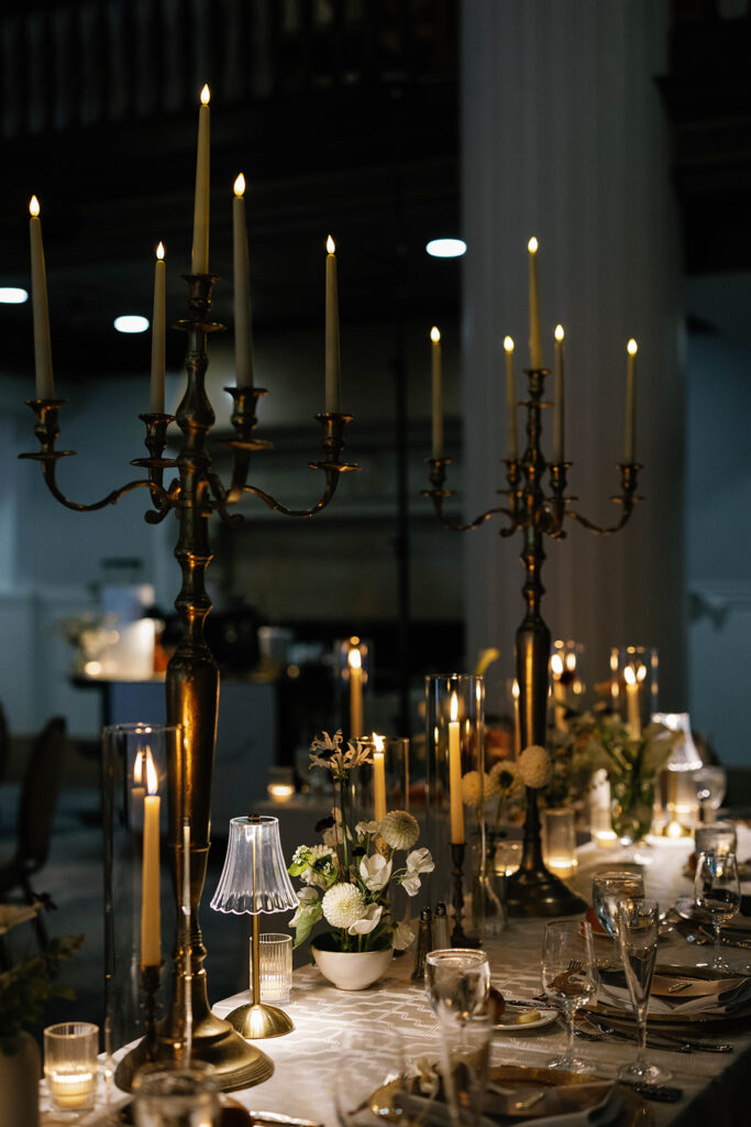 Candlelit reception table decorated with brass candelabras and white florals inside the Amway Grand Plaza Imperial Ballroom