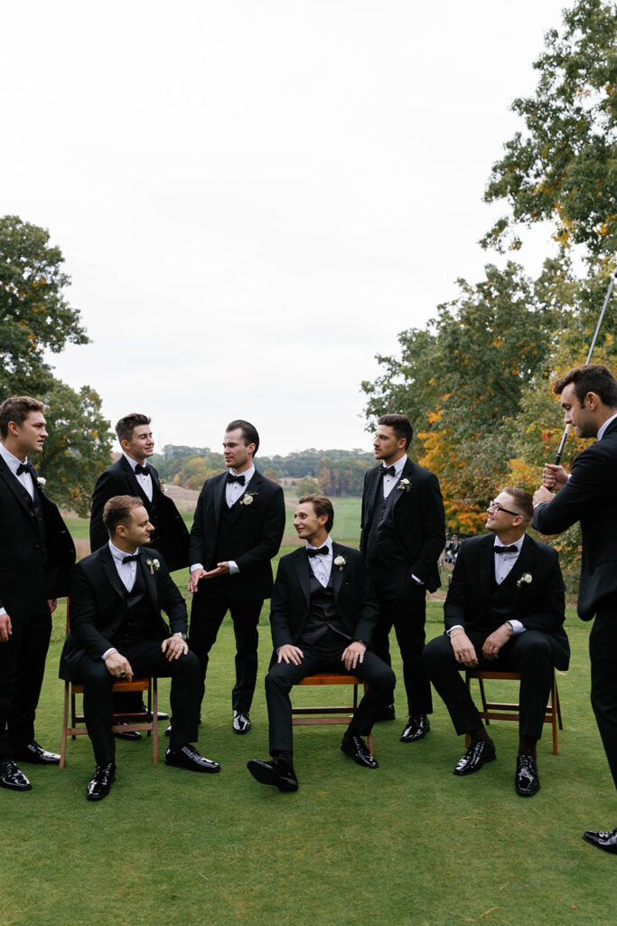 Candid editorial portrait of groom seated with groomsmen around him at The Mines Golf Course before Amway Grand Plaza wedding reception