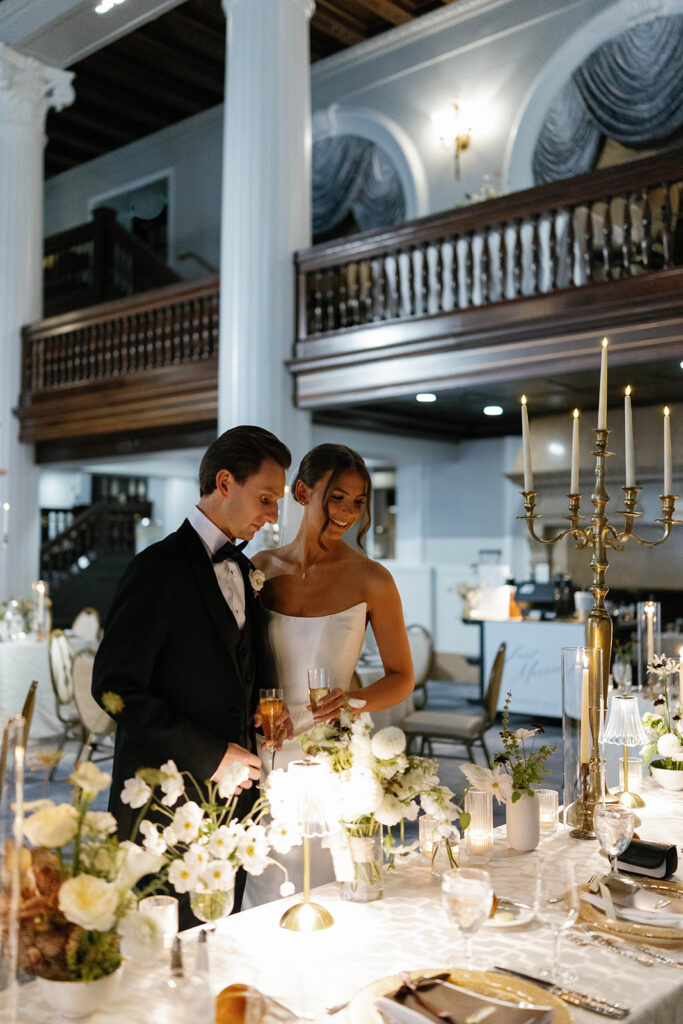Bride and groom admiring candlelit reception table decor inside the Imperial Ballroom at the Amway Grand Plaza