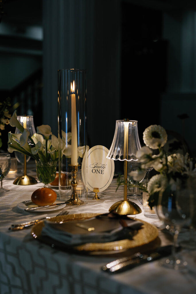 Elegant candlelit table setting with gold accents and white floral arrangements at the Amway Grand Plaza wedding reception