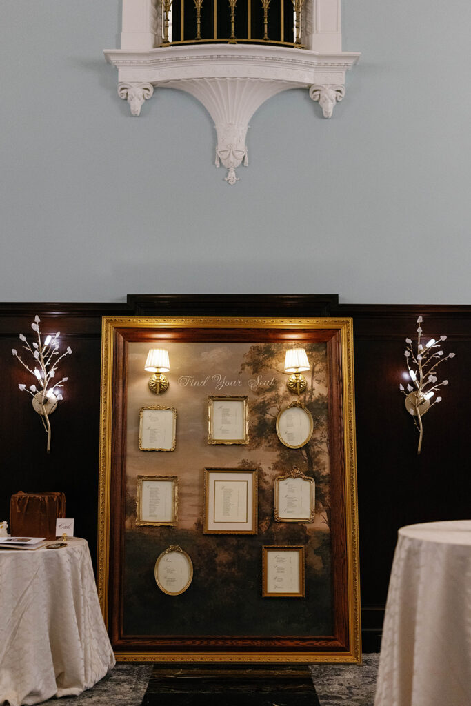 Vintage-inspired gold frame seating chart display in the Patlind Room at the Amway Grand Plaza wedding reception