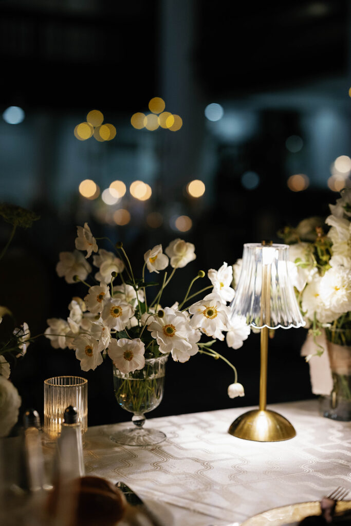 Close-up of white anemone floral centerpiece beside glass lamp at Amway Grand Plaza wedding reception