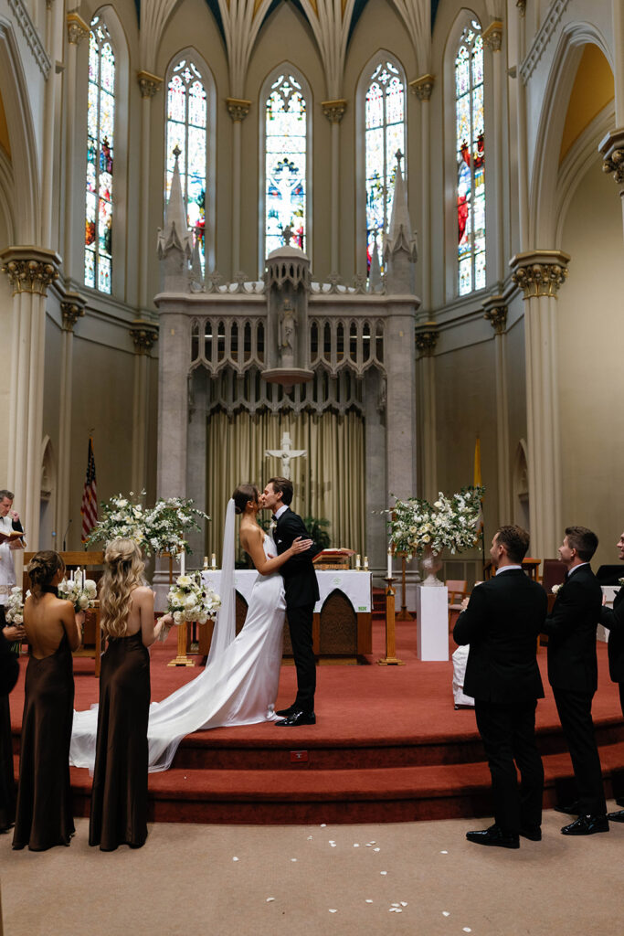 Bride and groom share their first kiss at the altar of St. Alphonsus Church in Grand Rapids during their Amway Grand Plaza wedding ceremony