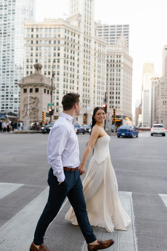 Chicago engagement photos couple crossing Michigan Avenue with Wrigley Building background